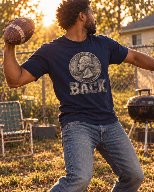 Man mid-throw in a backyard at golden hour wearing the navy Quarter Back tee — 1978 Washington quarter above BACK, YARD RULES